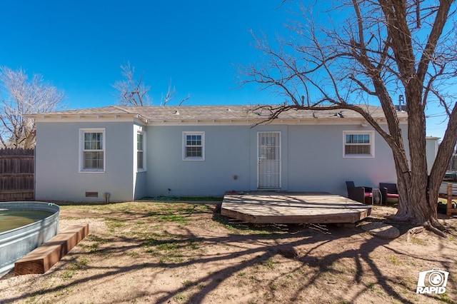 rear view of property with stucco siding, a shingled roof, crawl space, fence, and a wooden deck