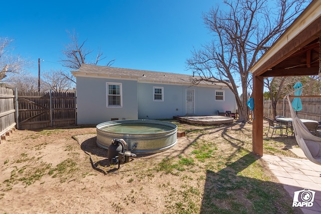 back of property featuring a hot tub, a patio area, a fenced backyard, and stucco siding