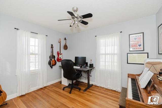 office featuring baseboards, a textured ceiling, a ceiling fan, and light wood-style floors