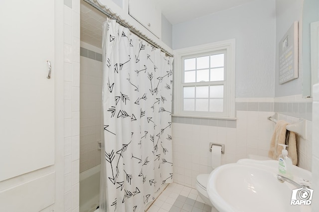 bathroom featuring wainscoting, shower / tub combo with curtain, tile patterned floors, a sink, and tile walls