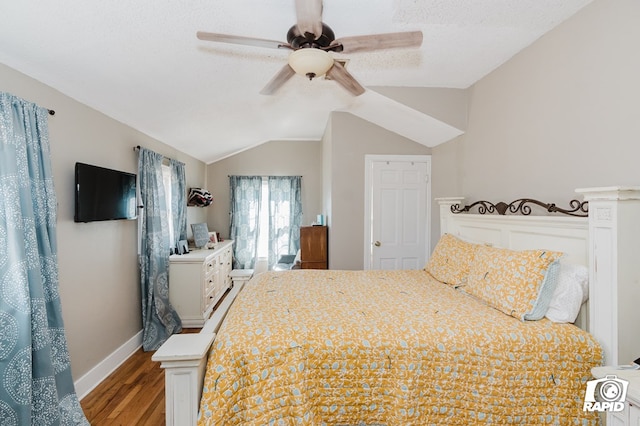 bedroom with ceiling fan, vaulted ceiling, a textured ceiling, wood finished floors, and baseboards