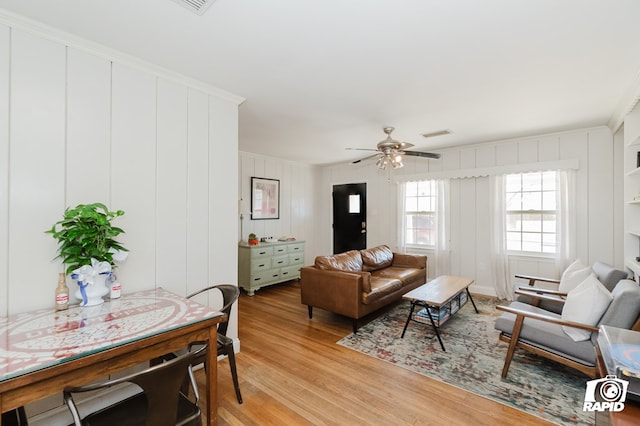 living room with light wood-style floors, visible vents, and a ceiling fan