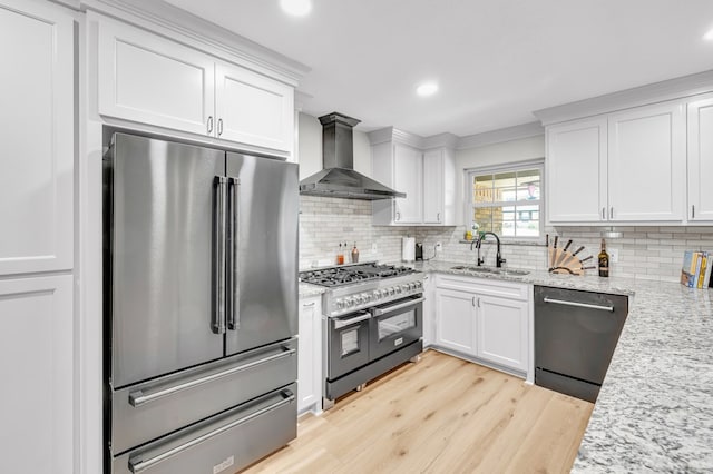10606 E County Rd 104, Midland, TX 79706 - kitchen with premium appliances, wall chimney range hood, light wood-style floors, white cabinets, and tasteful backsplash