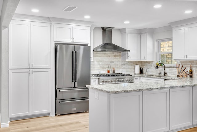 10606 E County Rd 104, Midland, TX 79706 - kitchen featuring stainless steel appliances, wall chimney exhaust hood, white cabinets, light stone countertops, and recessed lighting