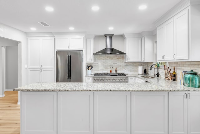 10606 E County Rd 104, Midland, TX 79706 - kitchen with stainless steel appliances, wall chimney exhaust hood, white cabinets, tasteful backsplash, and recessed lighting