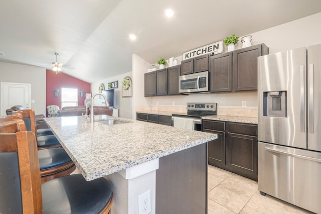 kitchen featuring sink, dark brown cabinets, stainless steel appliances, a kitchen breakfast bar, and a center island with sink