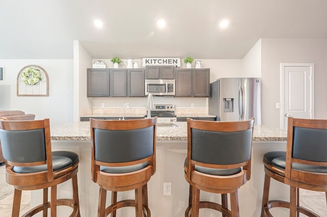 kitchen with stainless steel appliances, an island with sink, and a kitchen breakfast bar