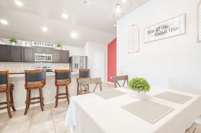 dining space with light tile patterned floors and vaulted ceiling