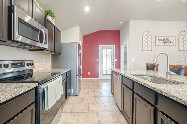 kitchen with dark brown cabinetry, sink, light stone counters, vaulted ceiling, and stainless steel appliances