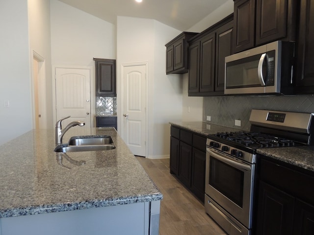 kitchen featuring a center island with sink, sink, hardwood / wood-style flooring, decorative backsplash, and stainless steel appliances