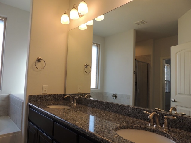 bathroom featuring a chandelier, shower with separate bathtub, and vanity