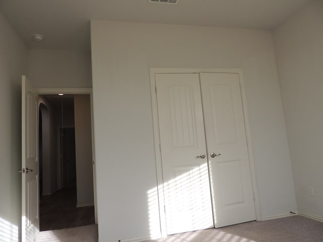 unfurnished bedroom with light carpet and a closet