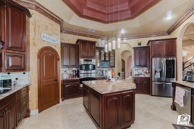 540 SE Loop 338, Odessa, TX 79766 - kitchen featuring appliances with stainless steel finishes, arched walkways, a tray ceiling, decorative backsplash, and a center island