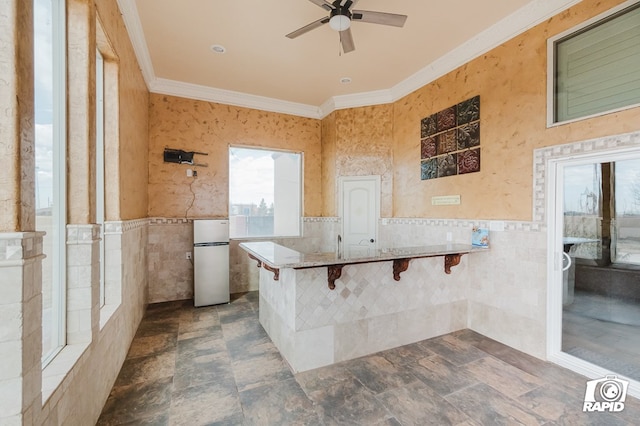 540 SE Loop 338, Odessa, TX 79766 - kitchen featuring freestanding refrigerator, tile walls, crown molding, ceiling fan, and a peninsula