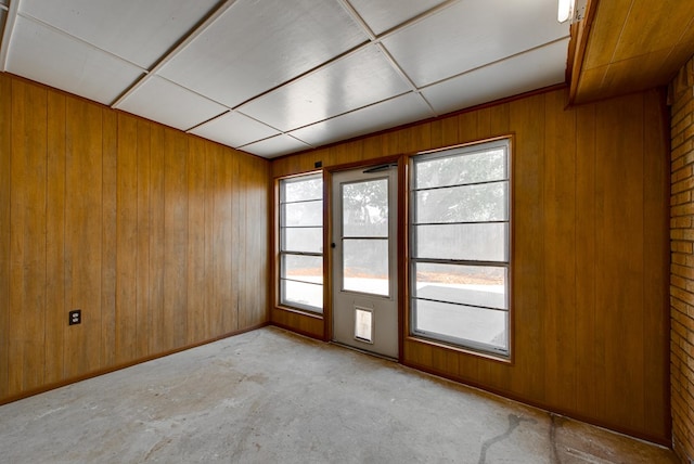 carpeted spare room with a paneled ceiling and wood walls