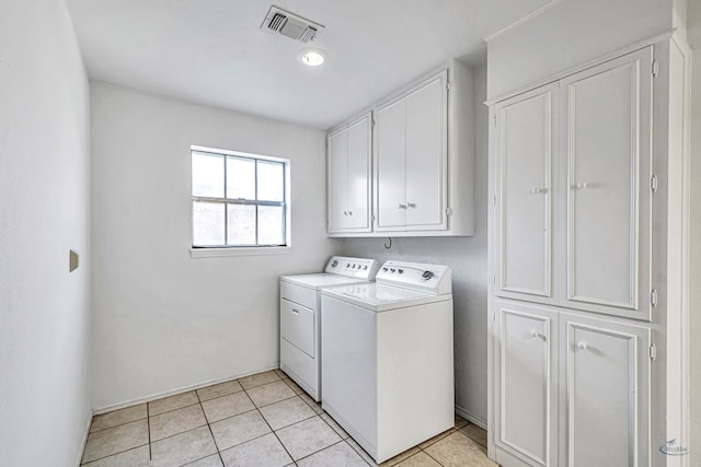 laundry room with cabinets, washing machine and dryer, and light tile patterned flooring