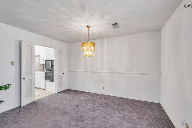 spare room featuring a chandelier and light colored carpet