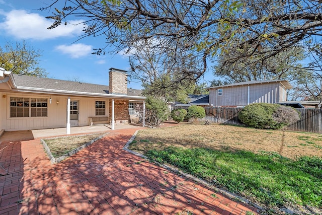 rear view of property featuring a patio area and a lawn