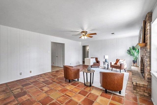 living room featuring a brick fireplace and ceiling fan