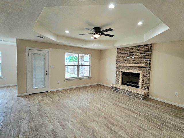 508 E Estes Ave, Midland, TX 79701 - unfurnished living room featuring a tray ceiling, light wood-style floors, ceiling fan, baseboards, and a fireplace