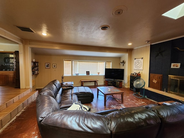 living room featuring a fireplace, hardwood / wood-style floors, a skylight, and a textured ceiling