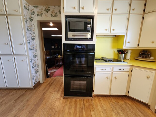 kitchen with white cabinets, black appliances, and light wood-type flooring