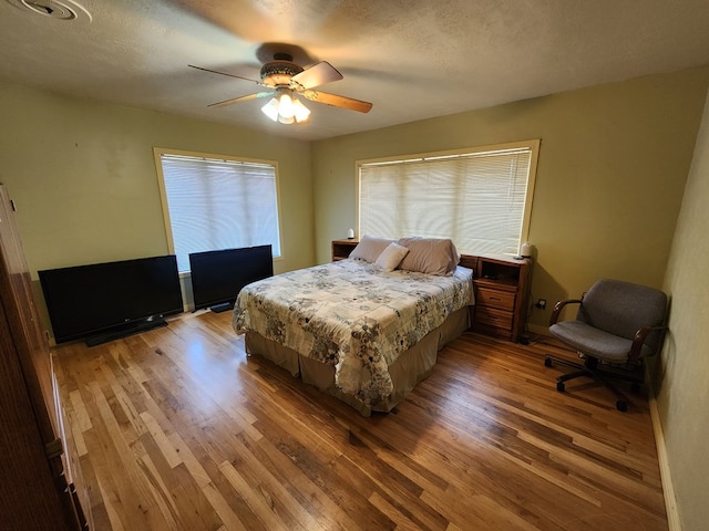 bedroom with wood-type flooring, a textured ceiling, and ceiling fan