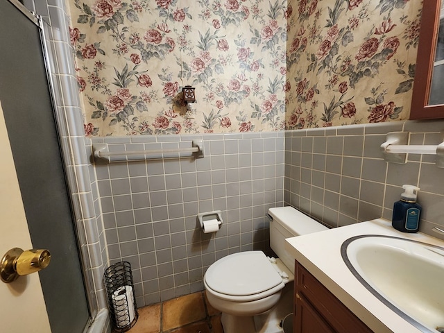 bathroom with vanity, toilet, tile walls, and a shower with shower door