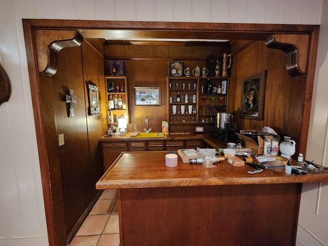 bar with butcher block countertops, light tile patterned floors, sink, and wooden walls