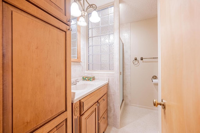 309 Edgewood Dr, Midland, TX 79703 - full bathroom featuring a shower with shower door, vanity, and a textured ceiling