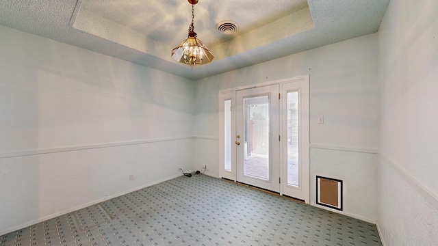 309 Edgewood Dr, Midland, TX 79703 - carpeted empty room featuring a chandelier, a raised ceiling, and a textured ceiling