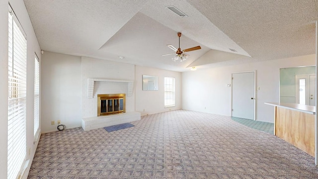 309 Edgewood Dr, Midland, TX 79703 - unfurnished living room featuring carpet floors, ceiling fan, a brick fireplace, vaulted ceiling, and a textured ceiling