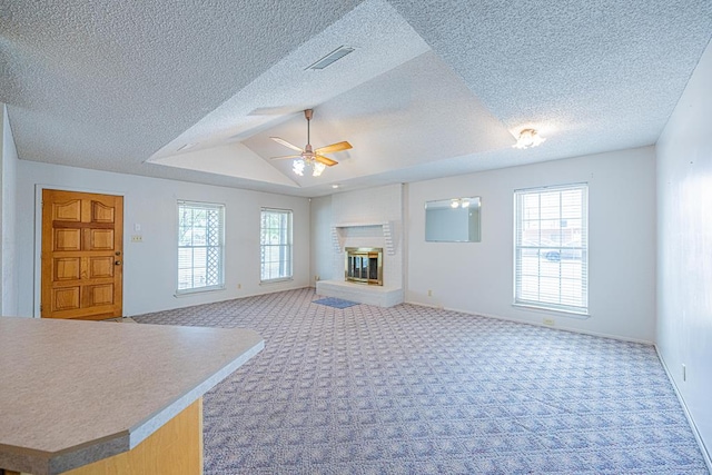 309 Edgewood Dr, Midland, TX 79703 - unfurnished living room with a ceiling fan, carpet flooring, a brick fireplace, vaulted ceiling, and a textured ceiling