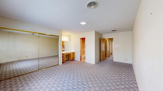 309 Edgewood Dr, Midland, TX 79703 - unfurnished bedroom featuring carpet flooring, a textured ceiling, connected bathroom, and a closet