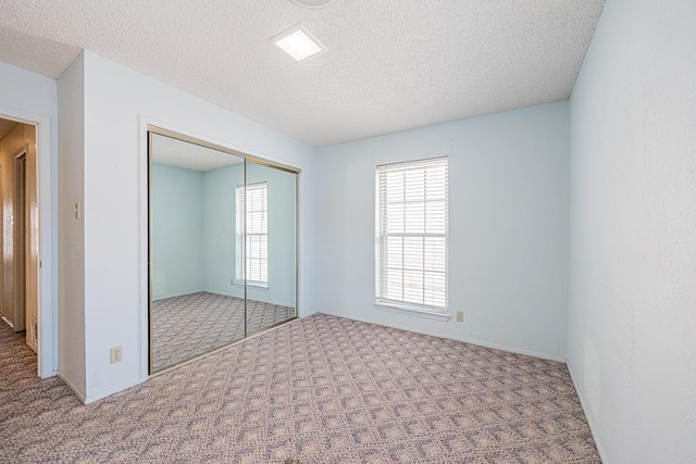 309 Edgewood Dr, Midland, TX 79703 - unfurnished bedroom featuring carpet flooring, multiple windows, a closet, and a textured ceiling