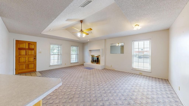 309 Edgewood Dr, Midland, TX 79703 - unfurnished living room with plenty of natural light, light colored carpet, a ceiling fan, a brick fireplace, and vaulted ceiling