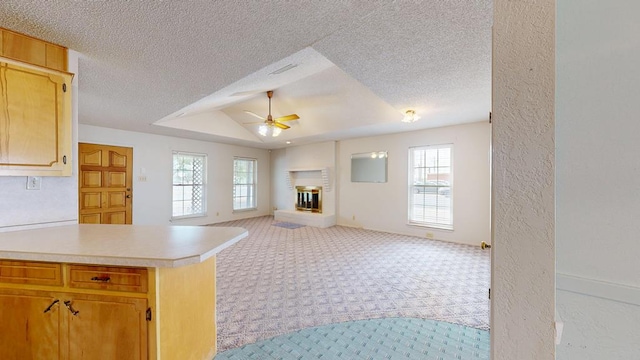 309 Edgewood Dr, Midland, TX 79703 - kitchen featuring a ceiling fan, light colored carpet, plenty of natural light, a fireplace, and a textured ceiling