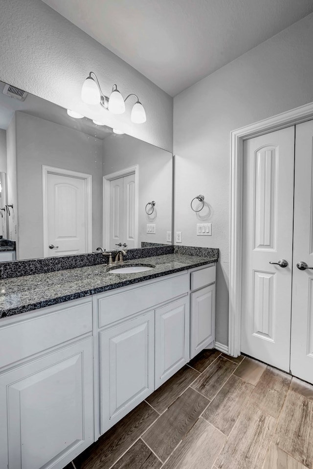 bathroom with visible vents, vanity, and wood tiled floor
