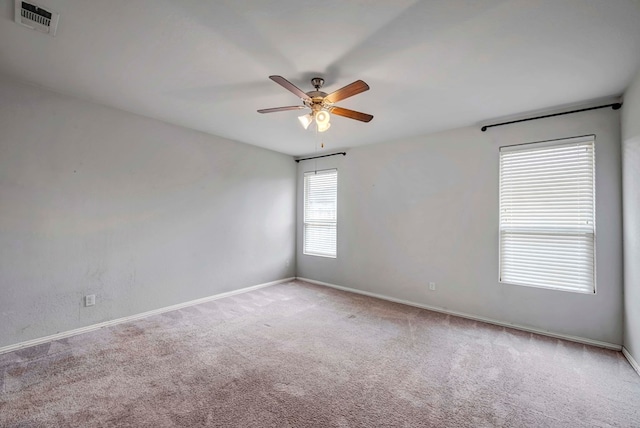 carpeted empty room featuring visible vents, a ceiling fan, and baseboards