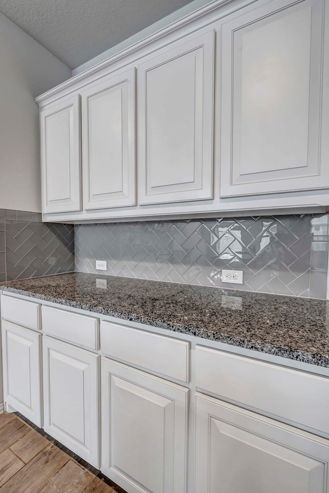 kitchen featuring tasteful backsplash, light wood-type flooring, white cabinetry, and dark stone countertops