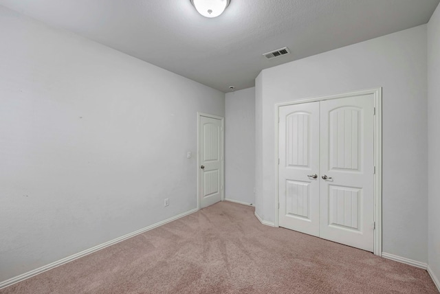 unfurnished bedroom featuring baseboards, carpet floors, visible vents, and a closet