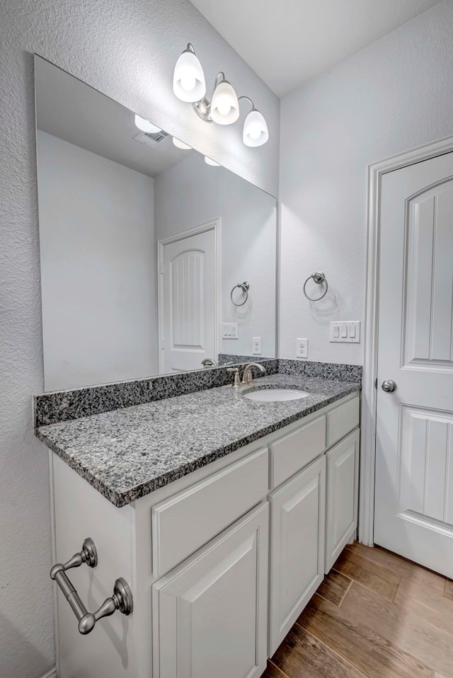 bathroom featuring wood finished floors, visible vents, and vanity