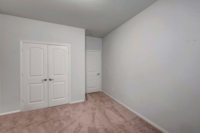 unfurnished bedroom featuring baseboards, light carpet, and a closet