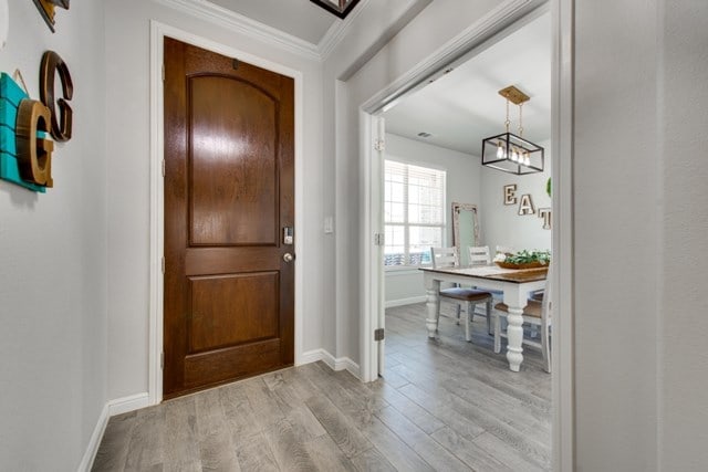 entryway with crown molding, baseboards, and wood finished floors