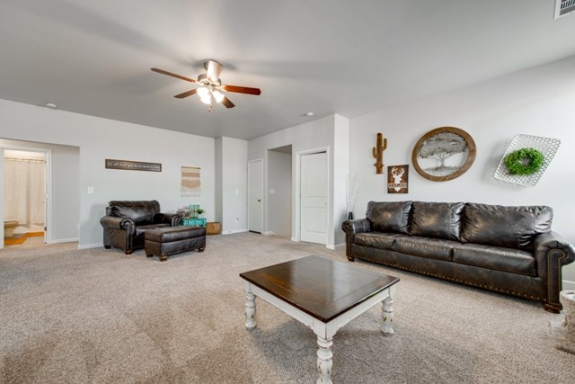 living room featuring visible vents, baseboards, ceiling fan, and carpet flooring