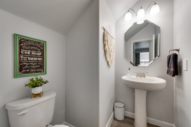 bathroom with toilet, baseboards, and a sink