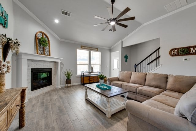 living room with visible vents, ornamental molding, wood finished floors, and vaulted ceiling