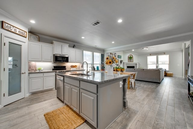 kitchen with a wealth of natural light, appliances with stainless steel finishes, crown molding, and a sink