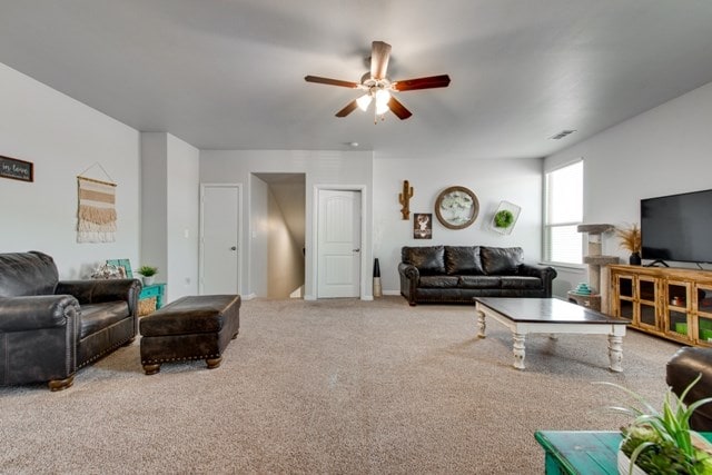 living area with a ceiling fan and carpet