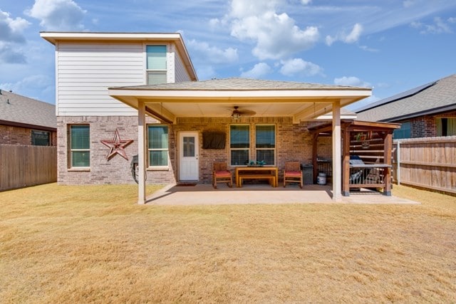 rear view of house with brick siding, a patio, a ceiling fan, and a fenced backyard